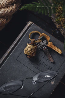 A vintage brass key resting on an aged wooden table beside a leather-bound book.