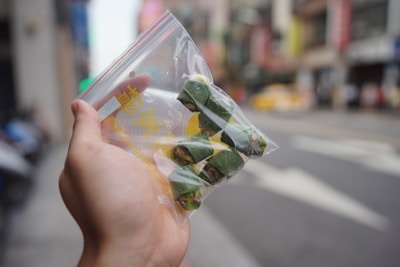 A delivery person holding a package with cannabis products in a city setting.