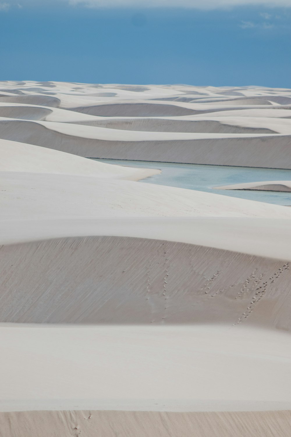 Eine große Fläche von Sanddünen mit einem Gewässer in der Ferne