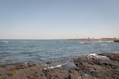 Engineers installing tidal energy equipment along a rocky shoreline surrounded by lush greenery.