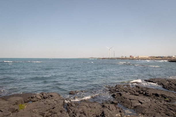 A coastal breakwater with waves crashing against it, showcasing energy generation equipment.