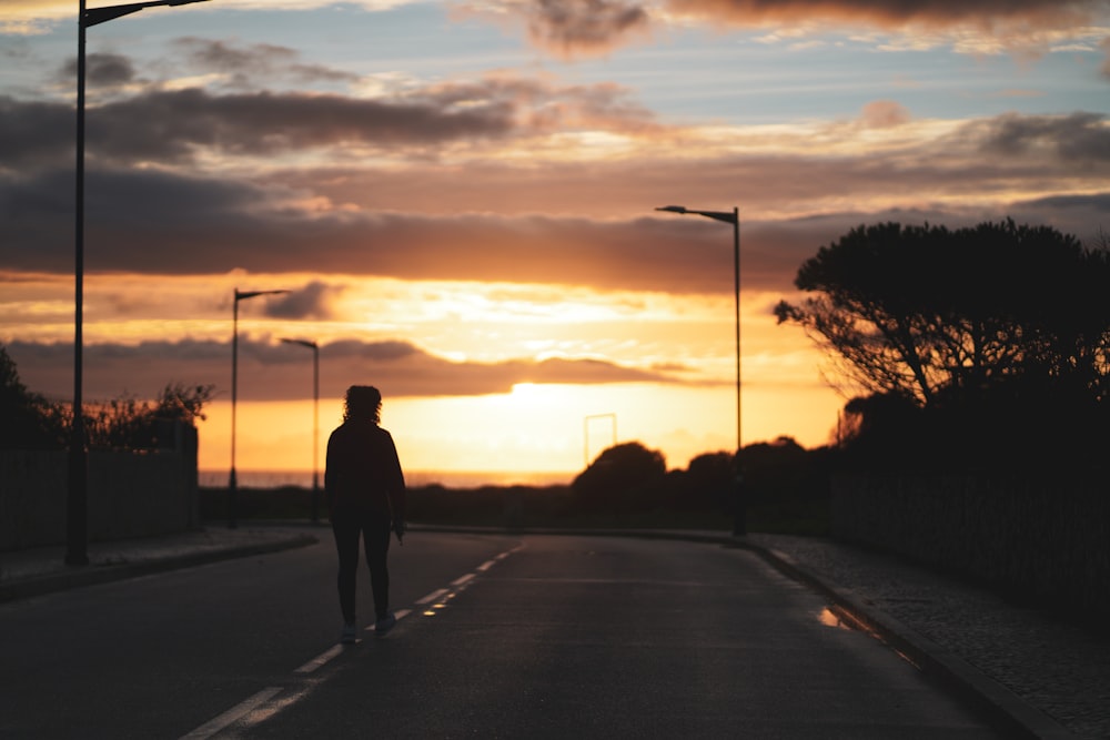 a person walking down a street at sunset