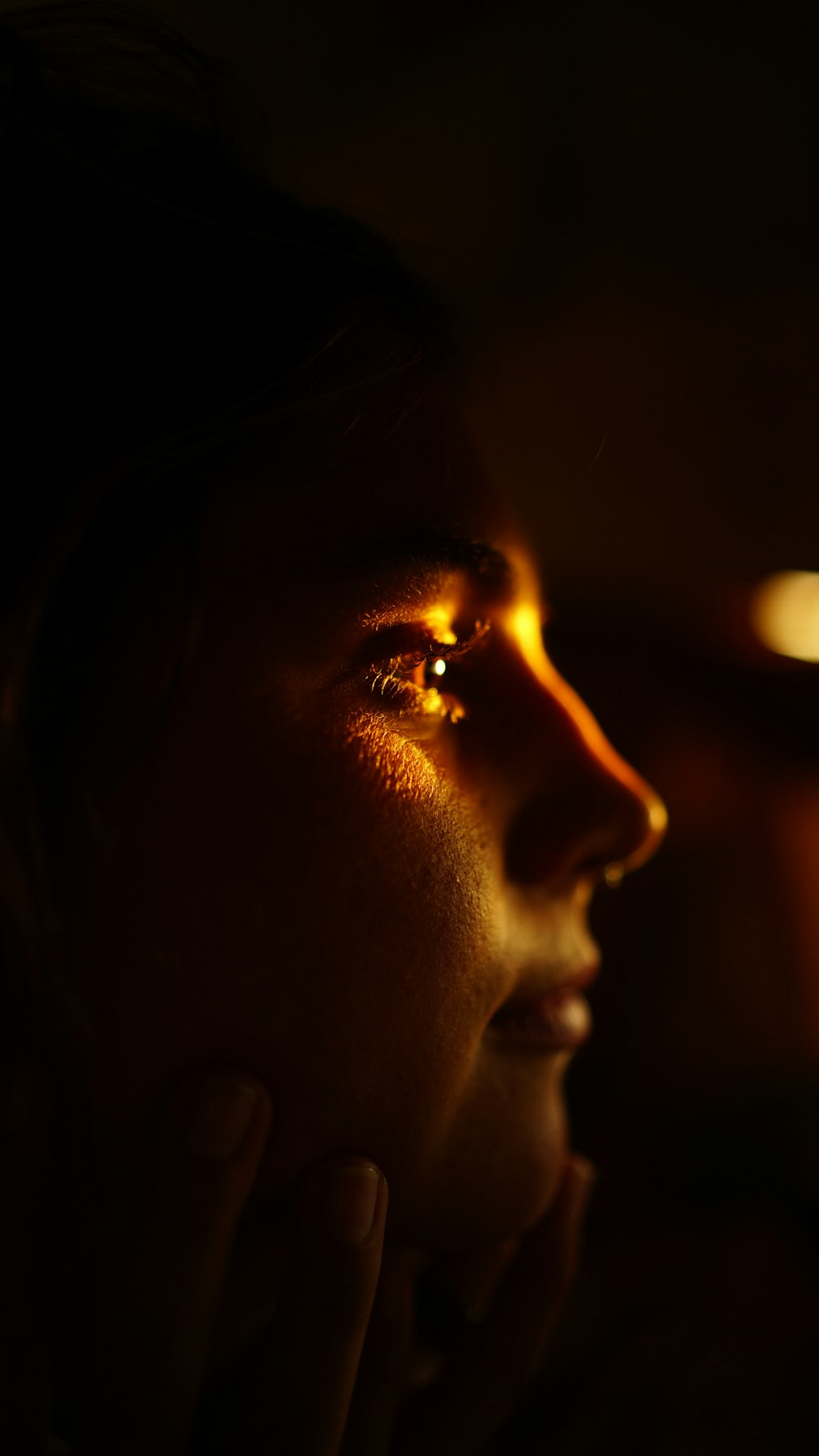 a woman in the dark with her hand on her face