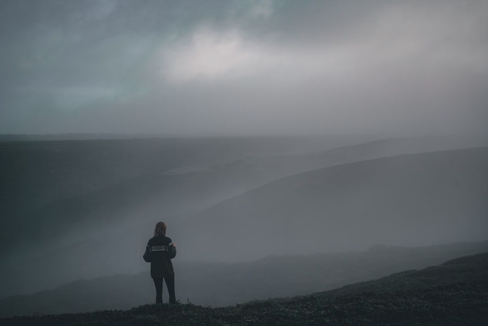 a person standing on top of a hill in the fog