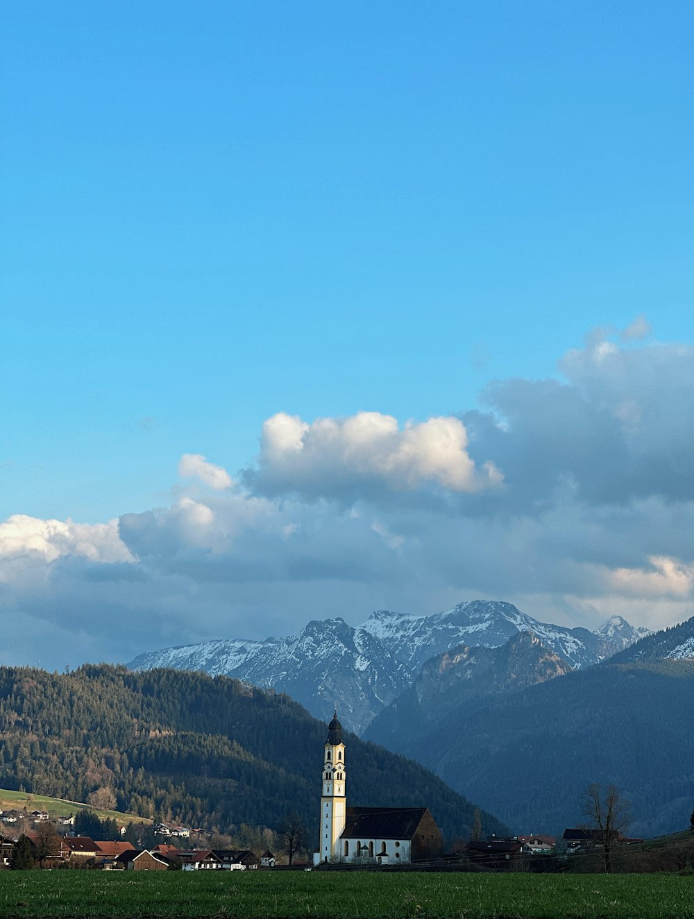 a church in the middle of a field with mountains in the background