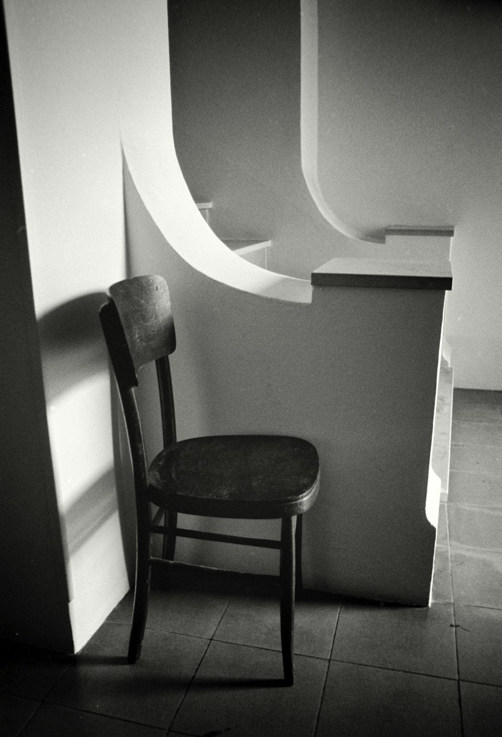 a black and white photo of a chair next to a wall