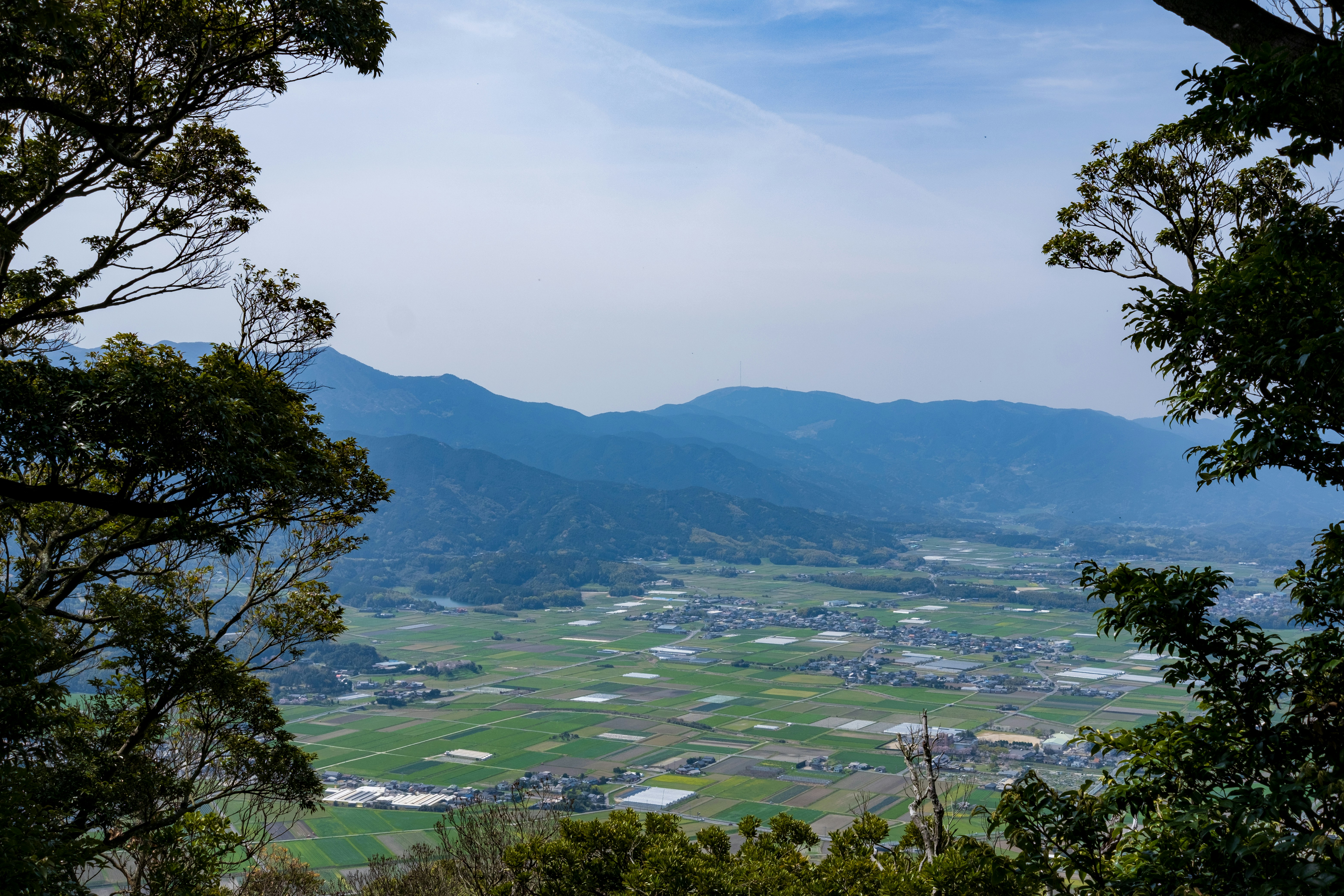 a view of a valley and mountains from the top of a hill