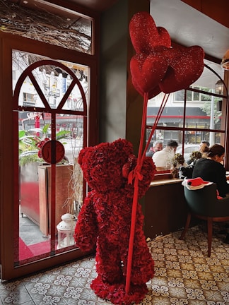 A cozy scene showing a couple wearing matching San Valentín themed shirts, surrounded by heart-shaped decorations.