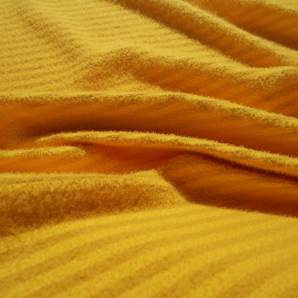 a close up of a bed with a yellow bedspread