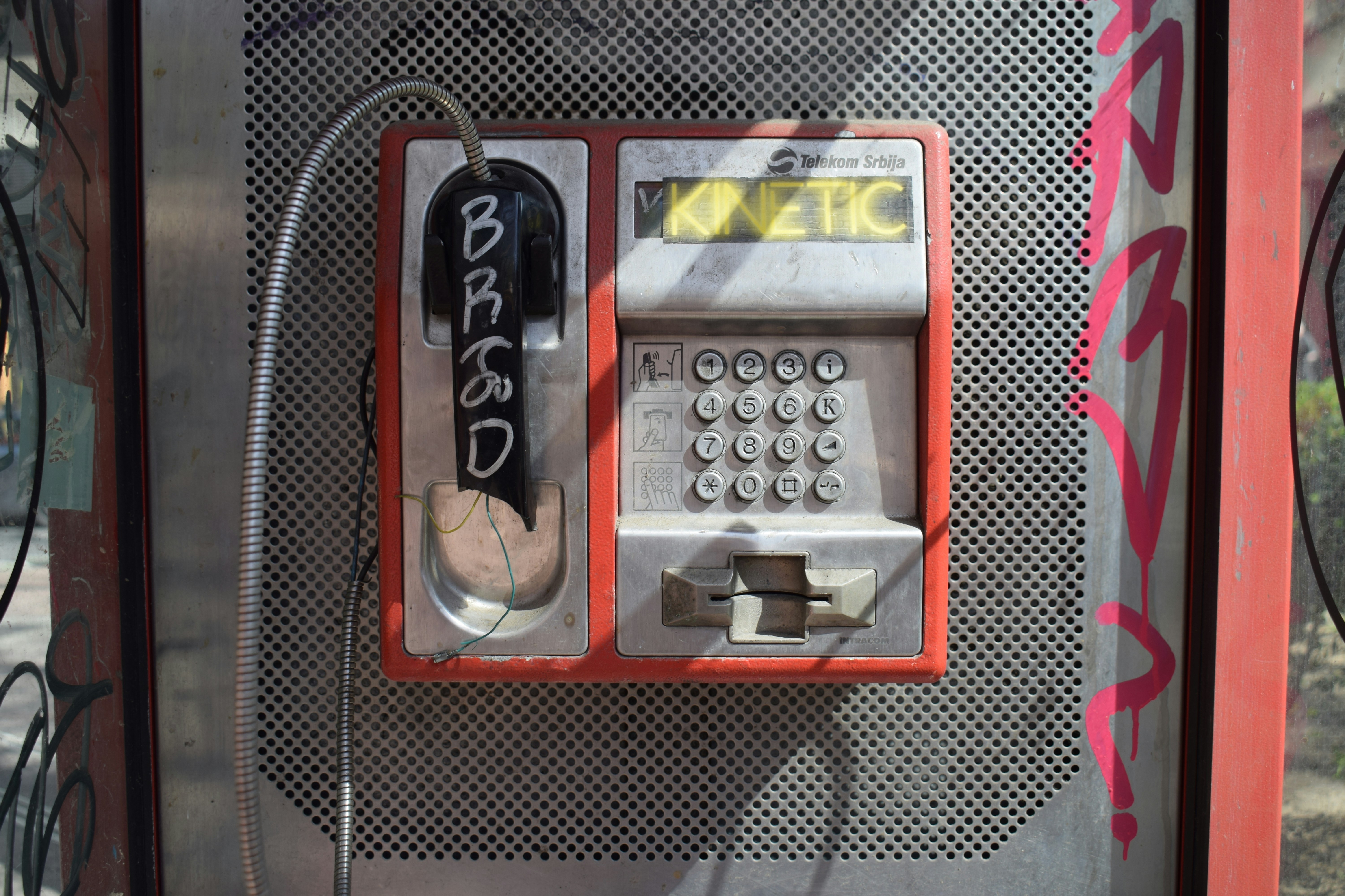 an old style pay phone with graffiti on it