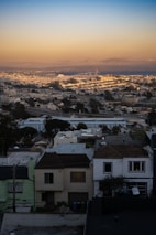 A cityscape view featuring various houses and apartment buildings at sunset.