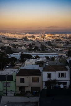 A cityscape view featuring various houses and apartment buildings at sunset.