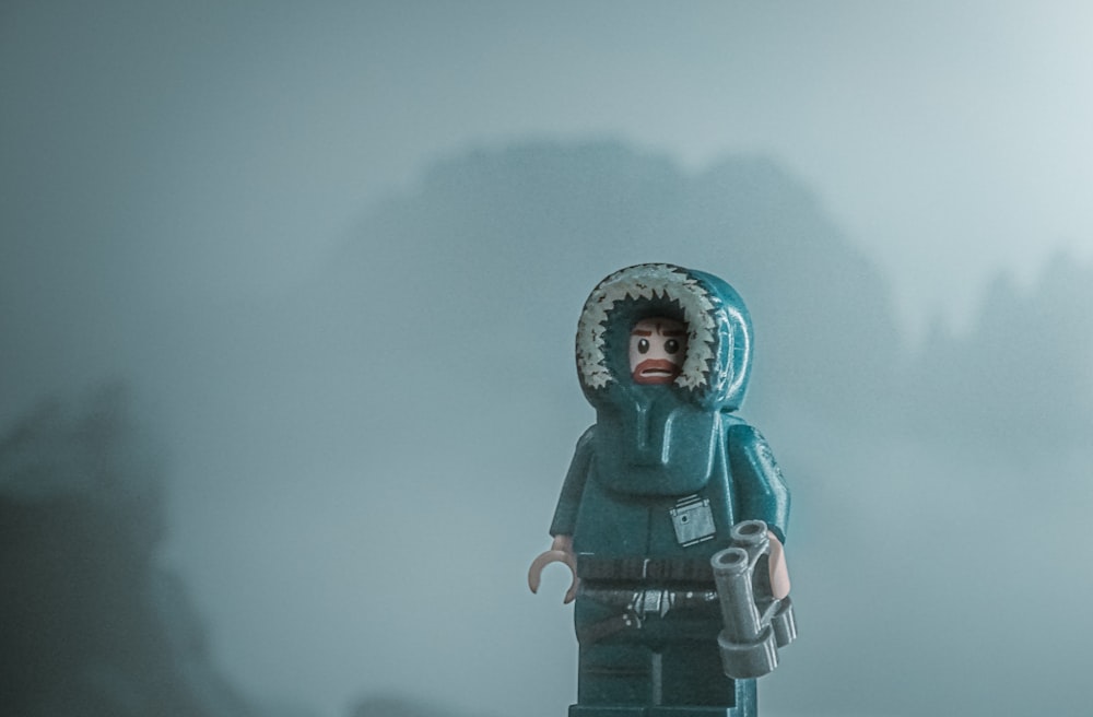 a lego figure with a hood on standing in the fog