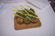 Golden, crispy arancini balls resting on a rustic wooden board with a side of marinara sauce.