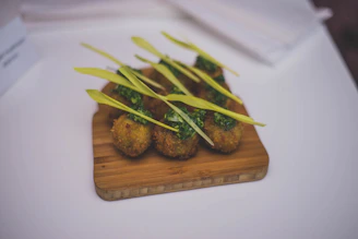 Close-up of golden, crispy takoyaki balls drizzled with sauce and sprinkled with green onions on a rustic wooden tray.