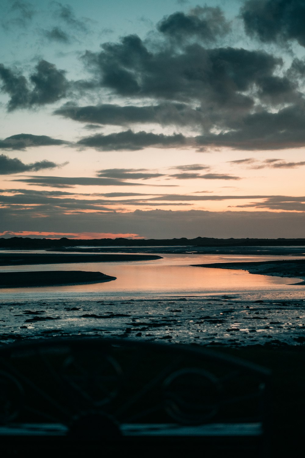 a body of water sitting under a cloudy sky