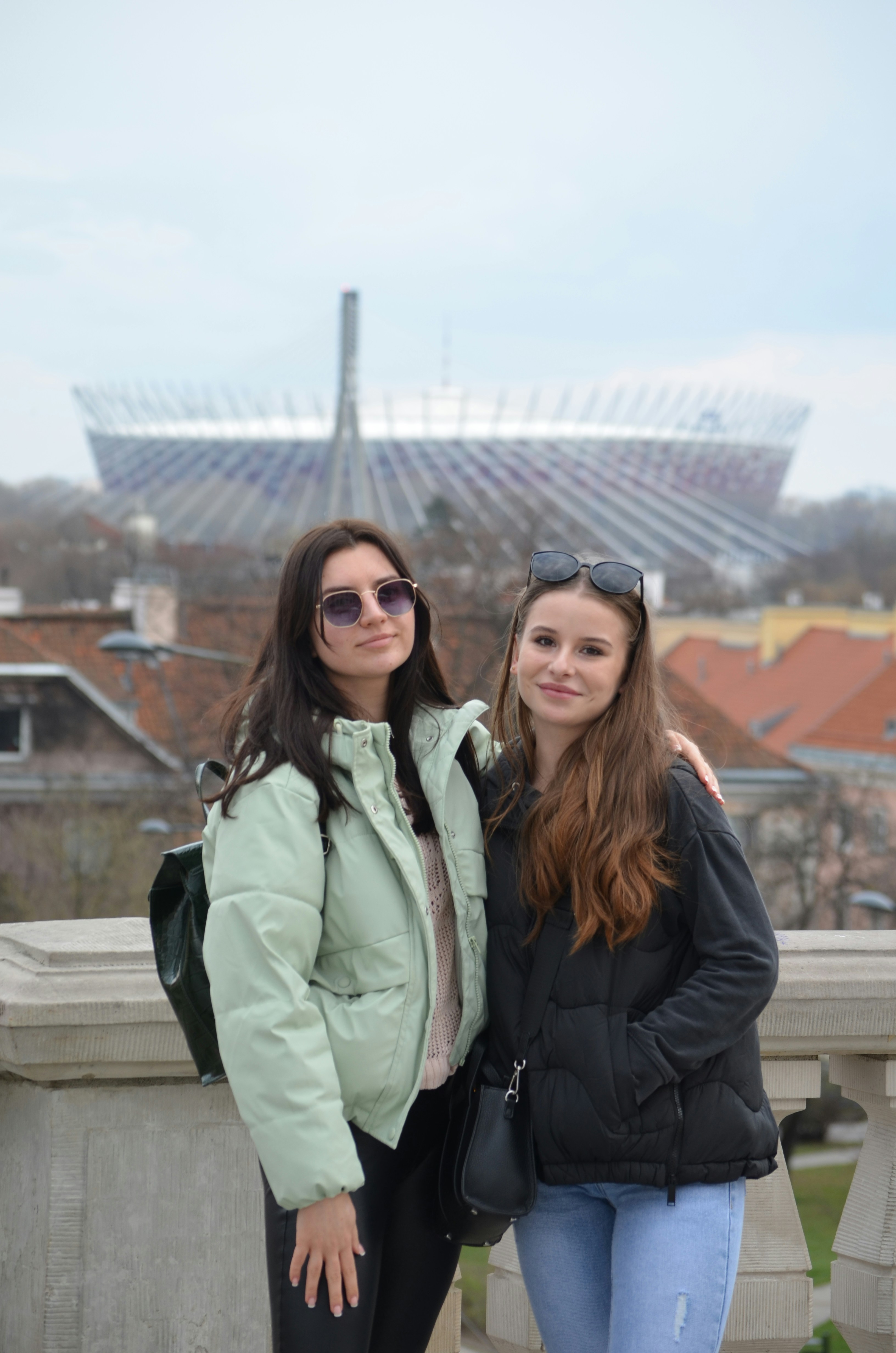 two women standing next to each other on a bridge