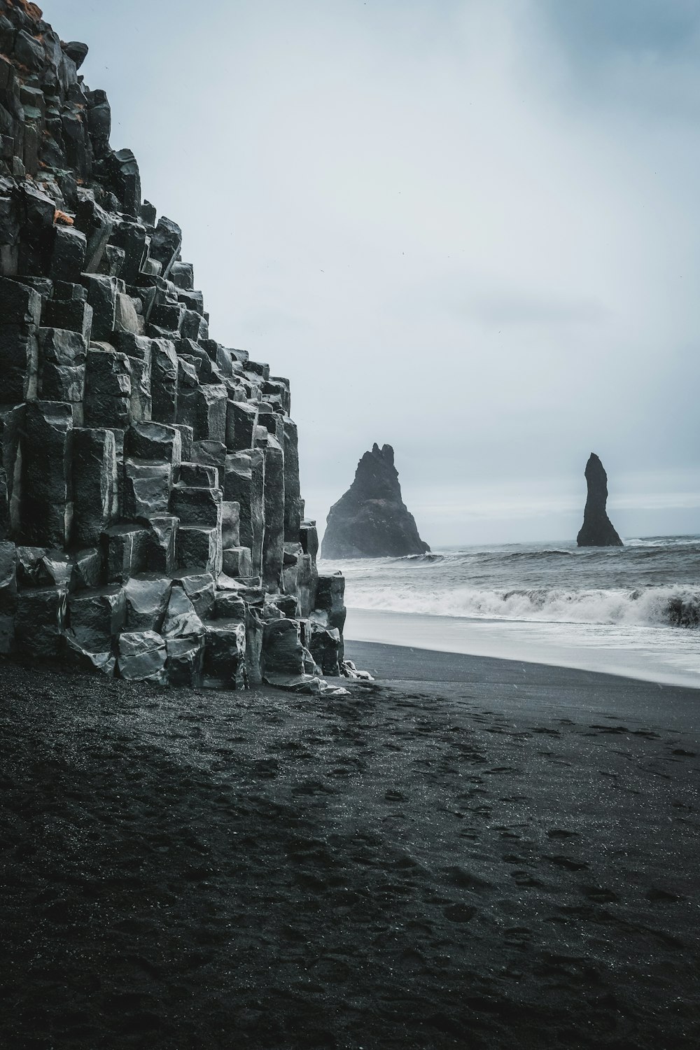 a large rock formation on a beach next to the ocean