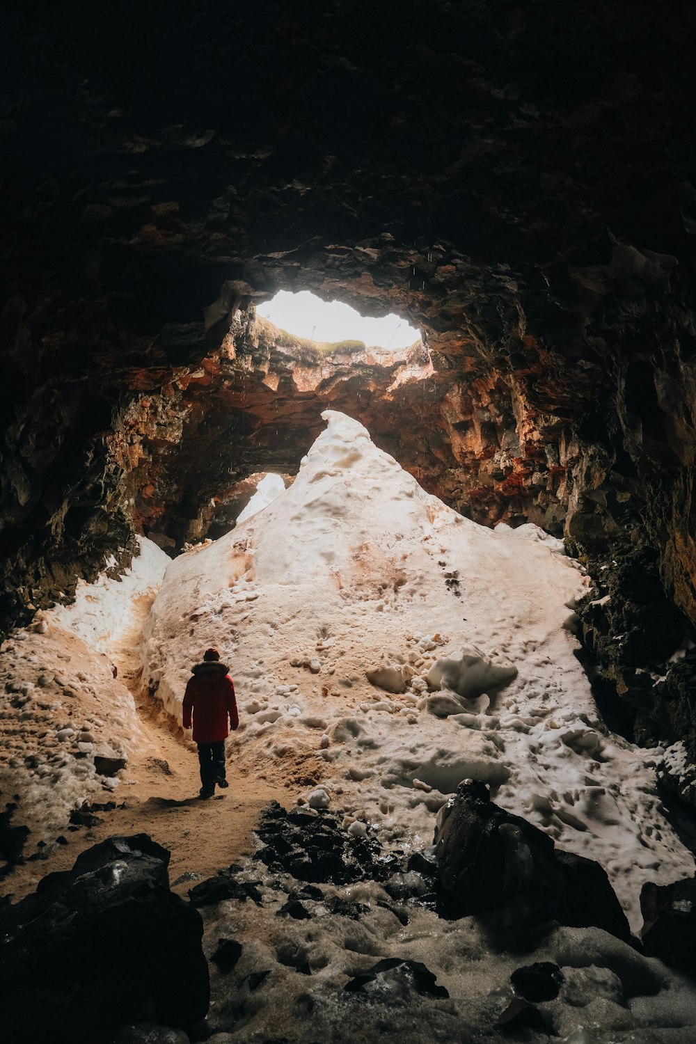 a person standing in a cave with snow on the ground
