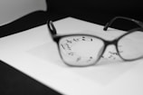 A pair of eyeglasses is placed on a piece of white paper featuring musical notes. The glasses are in sharp focus, highlighting the notes seen through the lenses, while the rest of the image is gently blurred.
