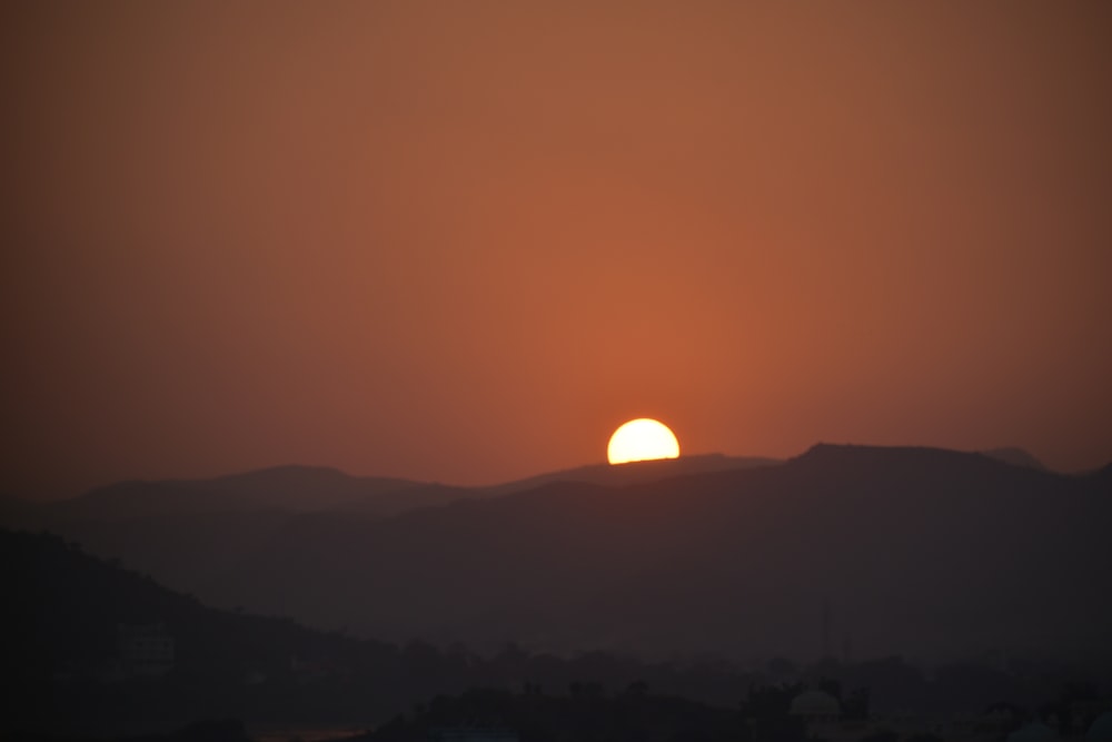 the sun is setting over a mountain range