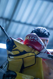 Close-up of boxing gloves hitting a heavy bag with sweat flying.