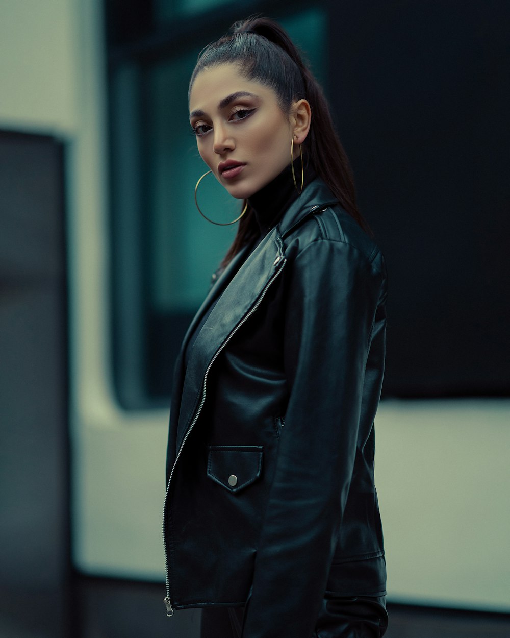 a woman wearing a black leather jacket and hoop earrings