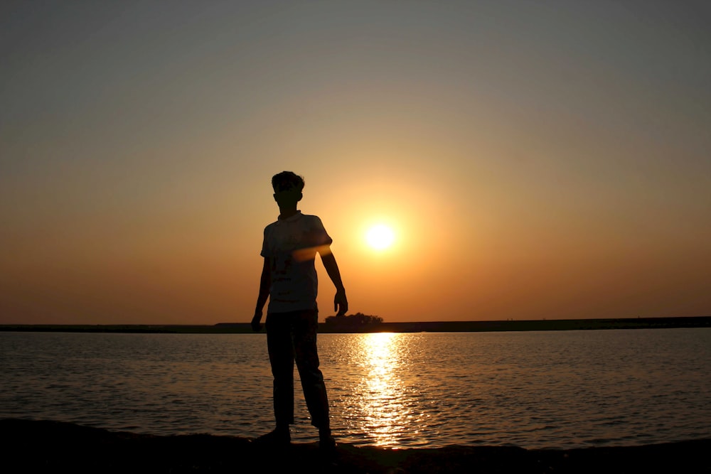 a person standing on a beach at sunset