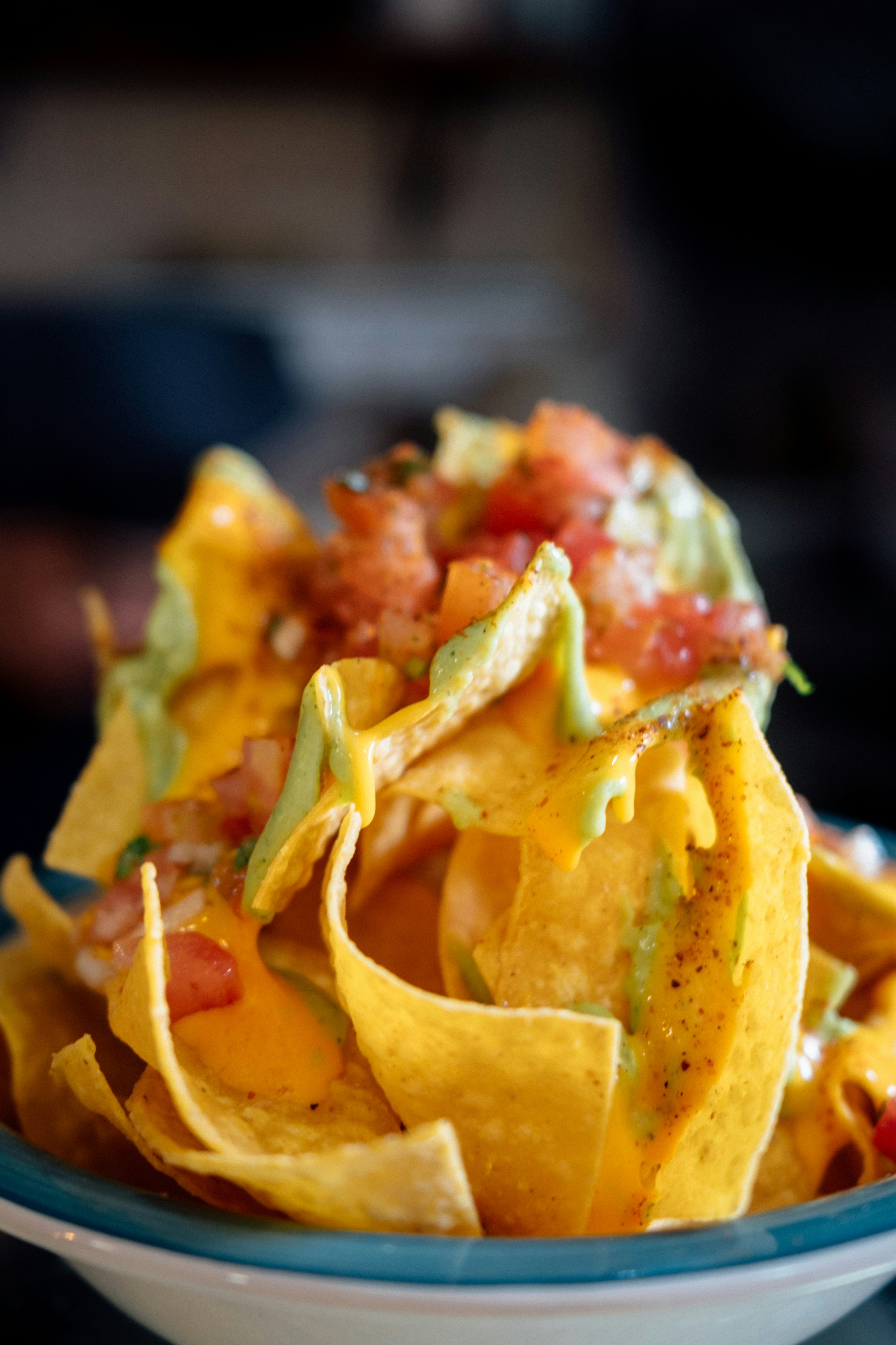 a bowl of nachos with tomatoes and avocado