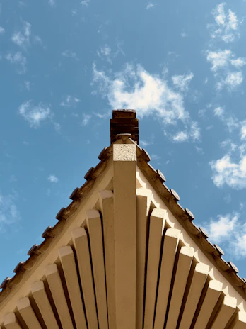 Sturdy roof construction with wooden beams and fresh shingles under a clear sky.