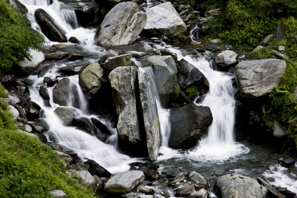 a stream of water surrounded by rocks and greenery