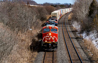 a red train traveling down train tracks next to a forest