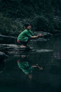 a woman kneeling on a rock in a river
