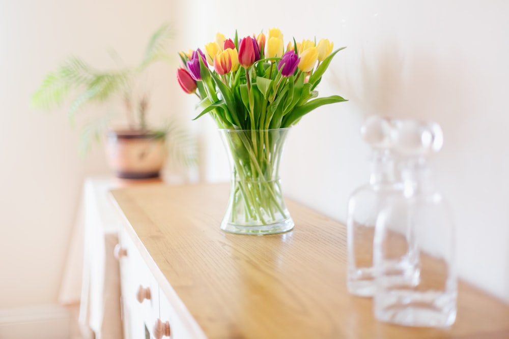 a vase filled with colorful flowers on top of a wooden table