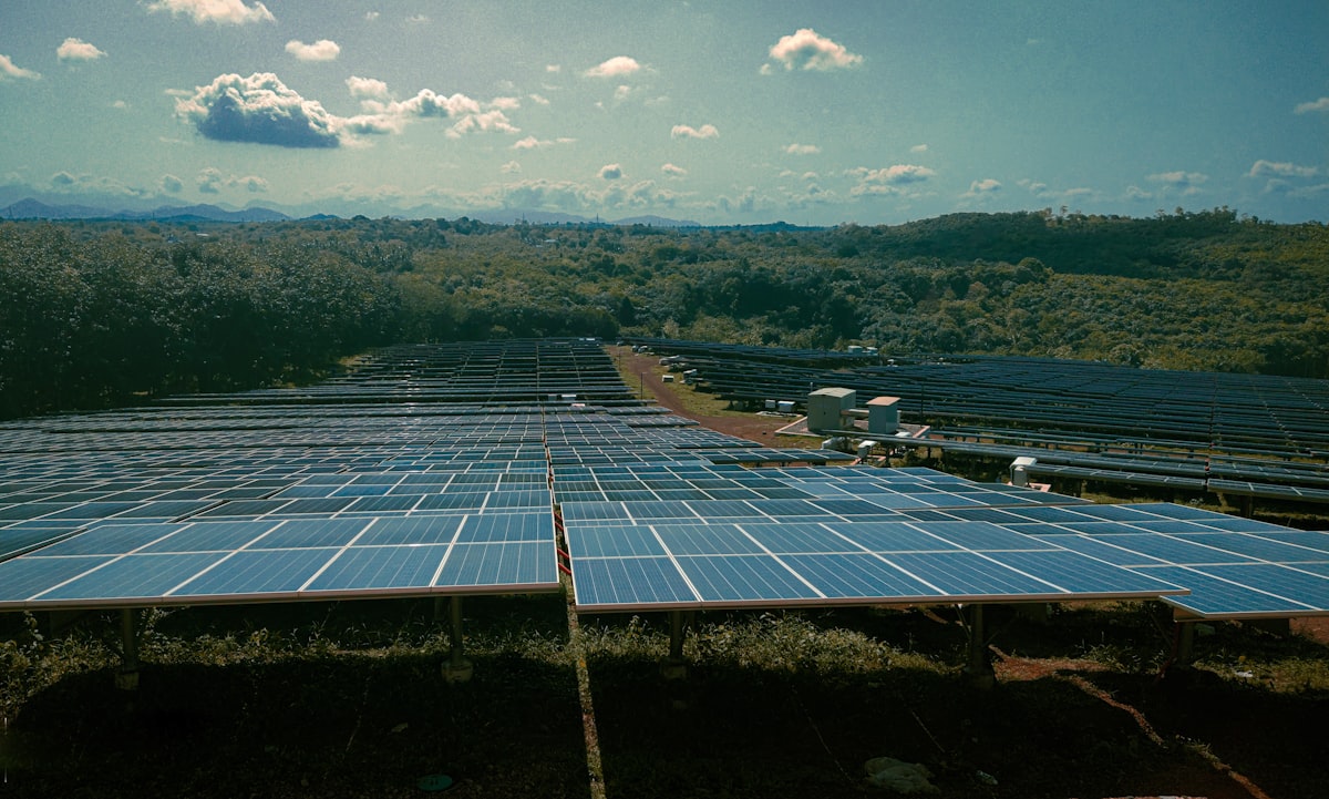 Rows of solar panels at a large solar farm stretching across a green field