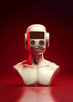 A futuristic sculpture of a humanoid bust with a smooth metallic finish. The head is designed like a retro robot with a rectangular visor and twin circular eyes, set against an intense red gradient background.