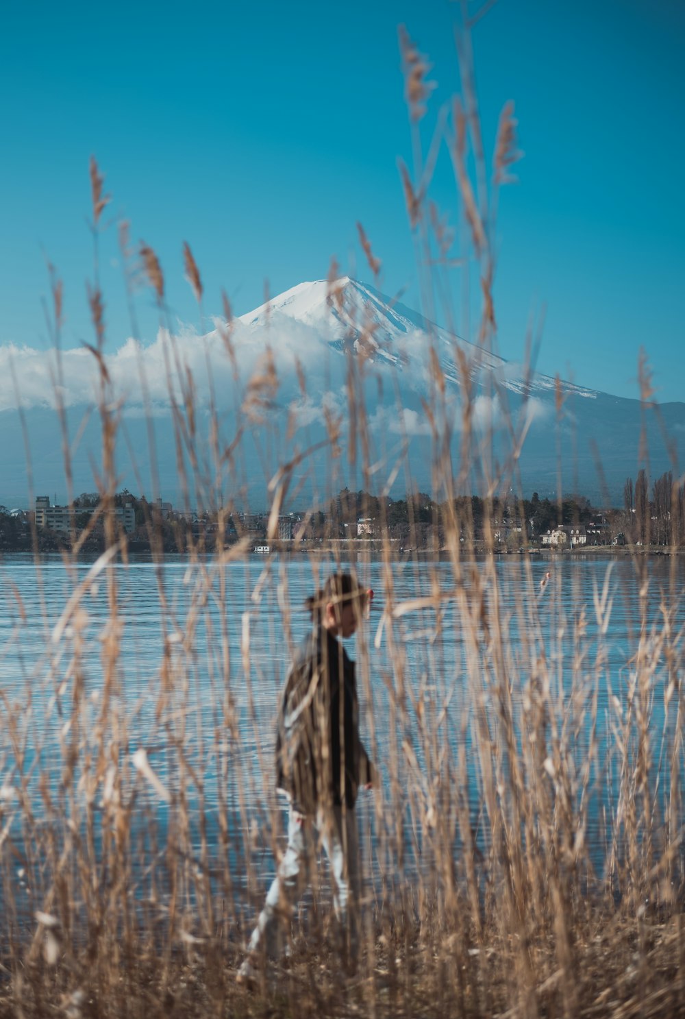 a man walking by a lake with a mountain in the background