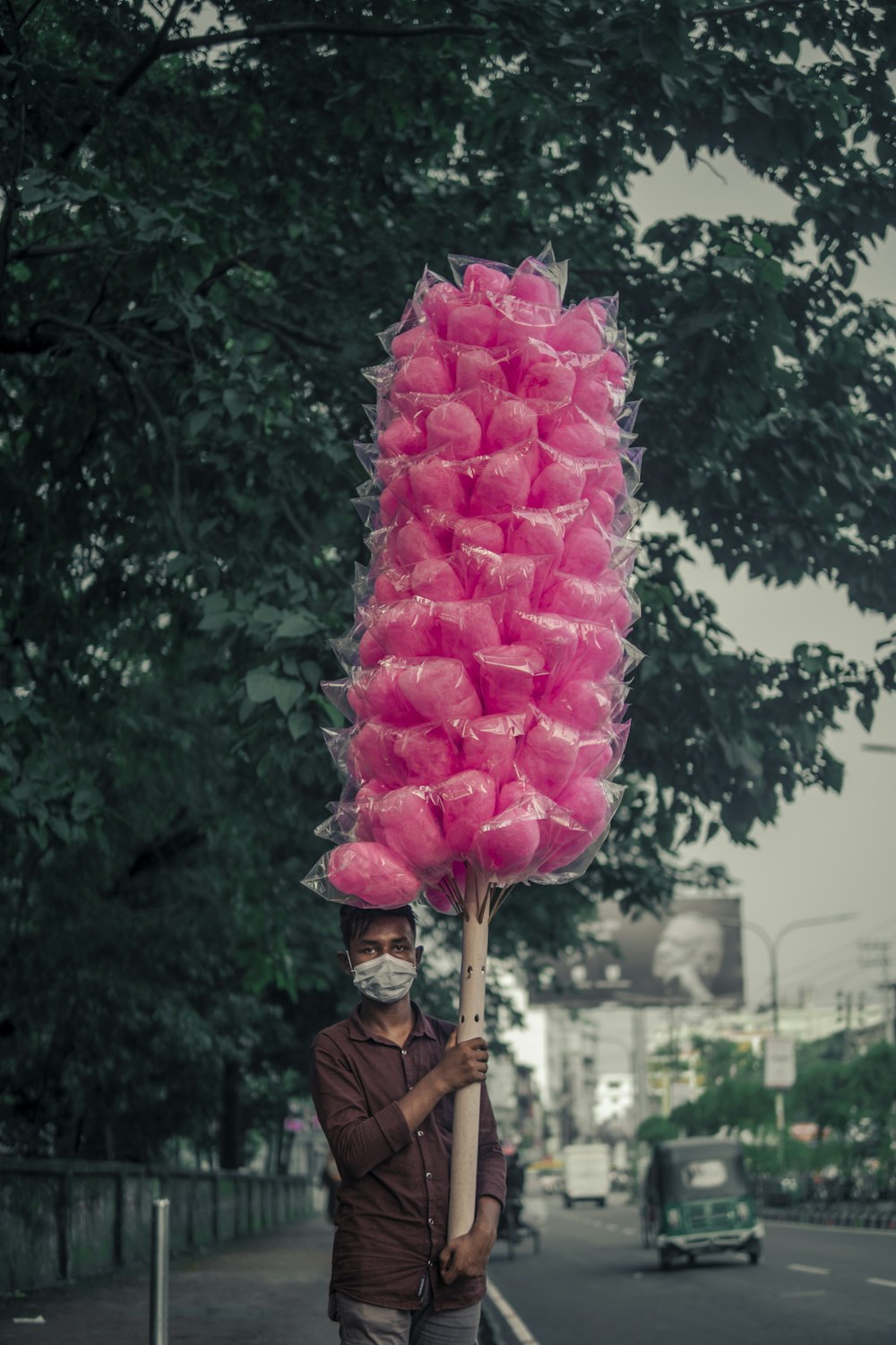 a man holding a giant pink lollipop on a street