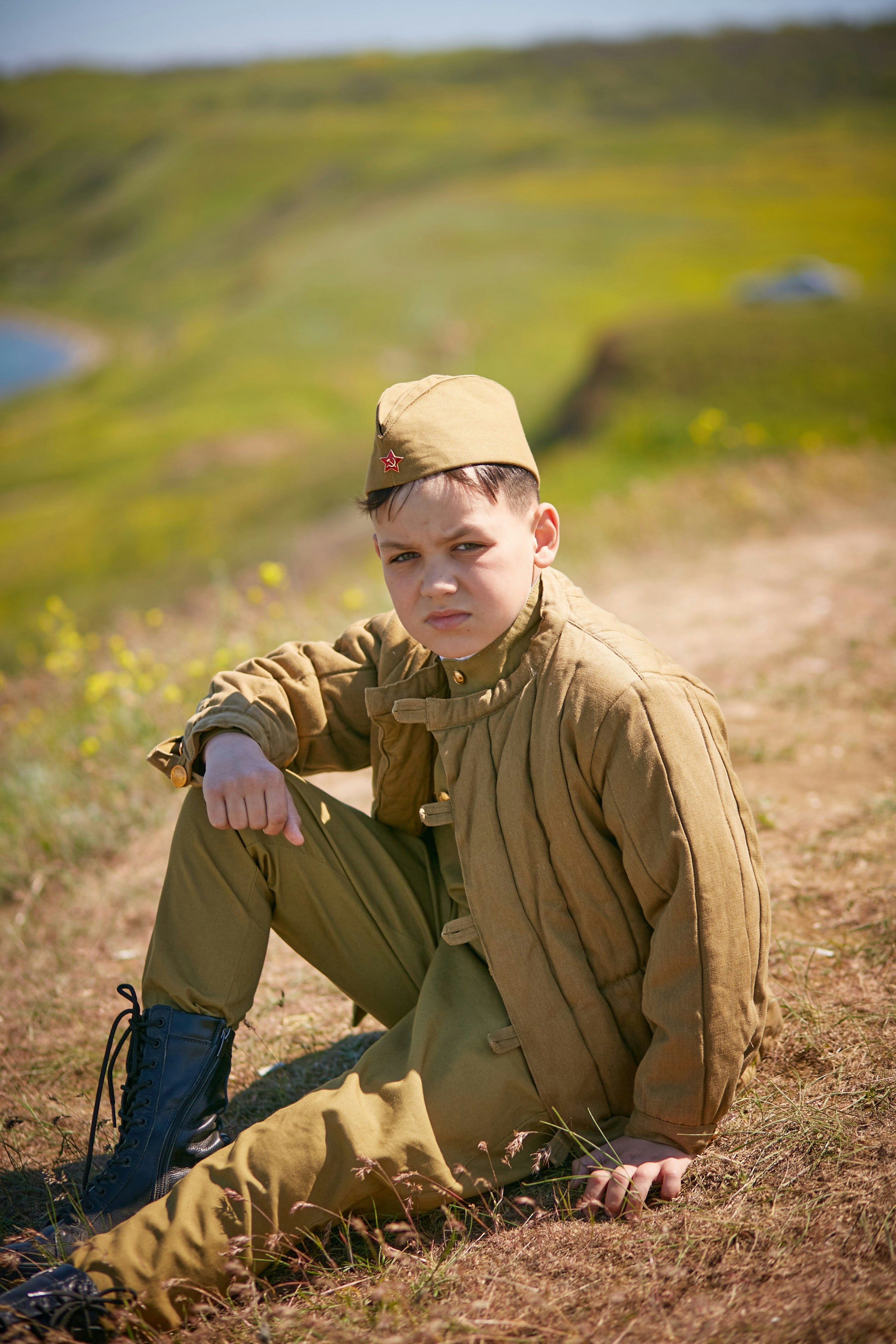 a young boy sitting on the ground in a field