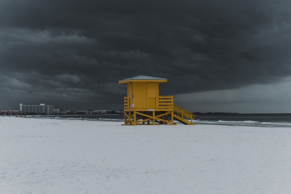 a yellow lifeguard tower sitting on top of a sandy beach
