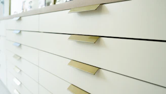 a close up of a white dresser with brass handles