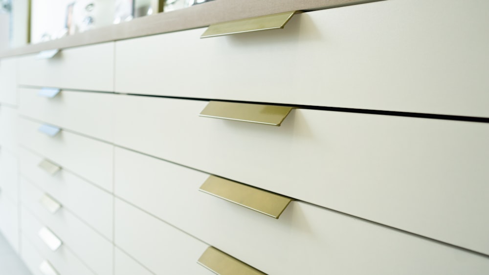 a close up of a white dresser with brass handles