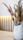 Elegant shot of a minimalist vase on a wooden shelf with soft beige walls in the background.