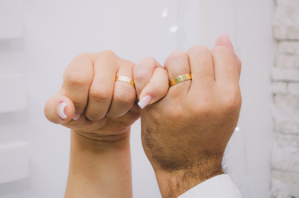 a man and a woman holding hands with wedding rings on their fingers