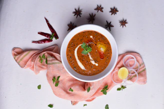 A steaming bowl of rich, spicy chicken curry garnished with fresh coriander.