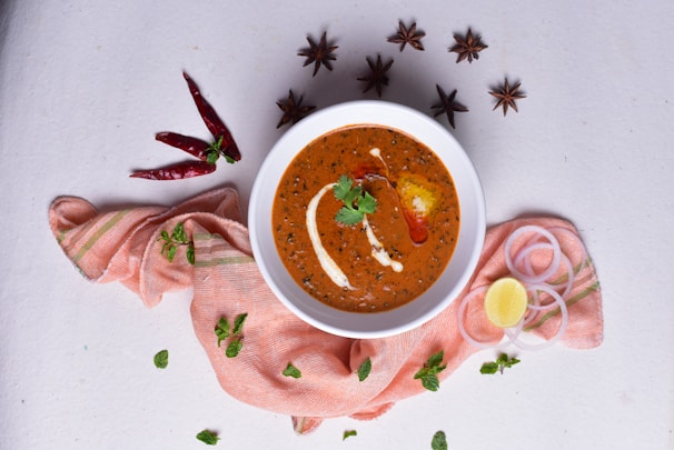 Close-up of a steaming curry bowl with rich, aromatic spices, garnished with fresh cilantro and a wedge of lime.