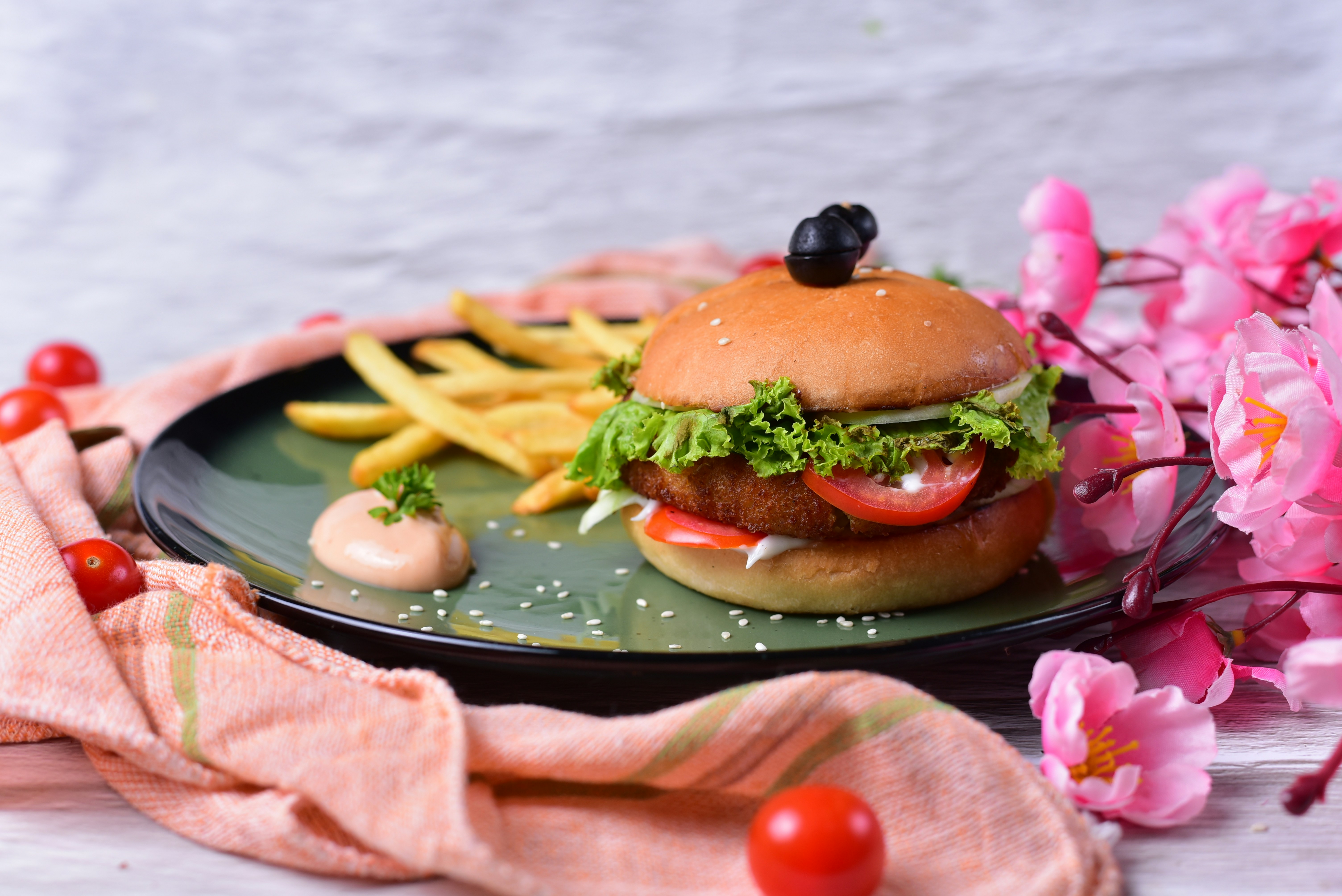 Burger with fries on a dark plate with flowers