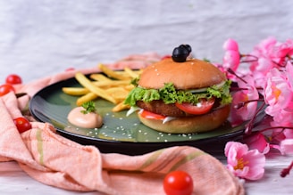 A colorful plate featuring a veg burger with fresh lettuce and tomato, served with crispy fries on the side.