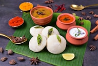 Freshly prepared idlis and chutney served in a traditional stainless steel plate.