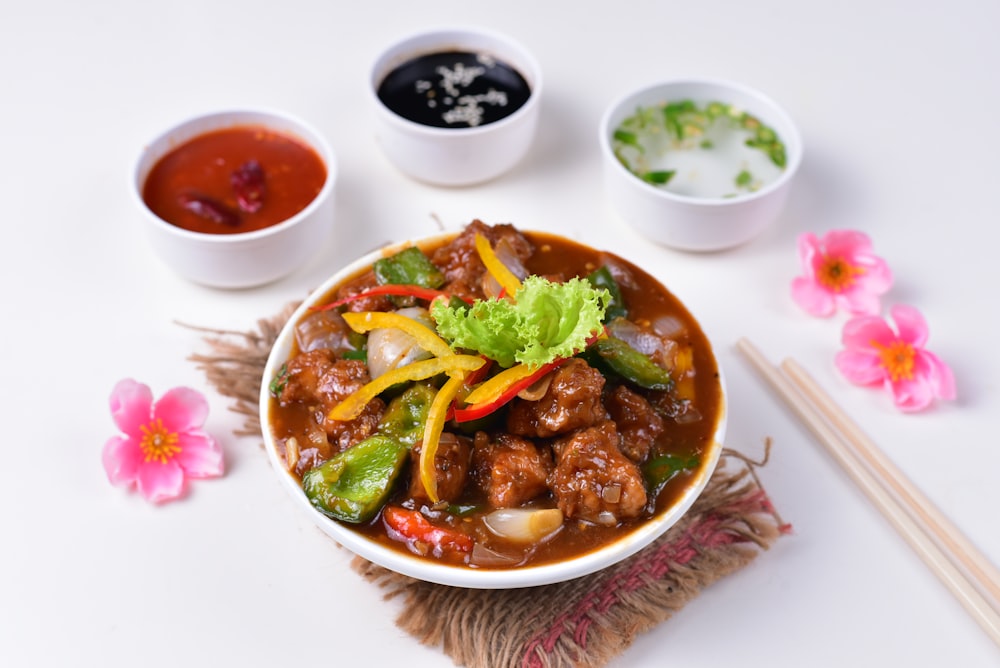 a bowl of food with chopsticks next to it